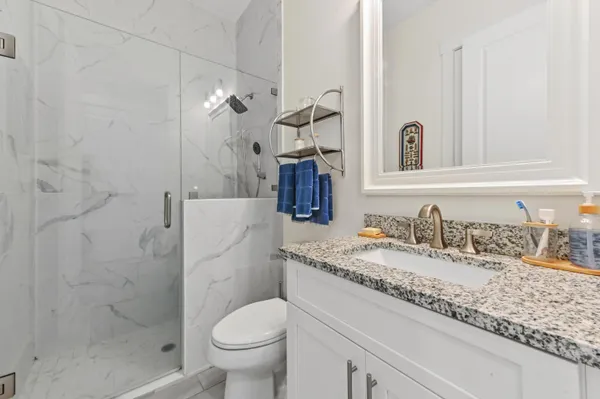 a bathroom with a granite countertop sink a toilet and shower