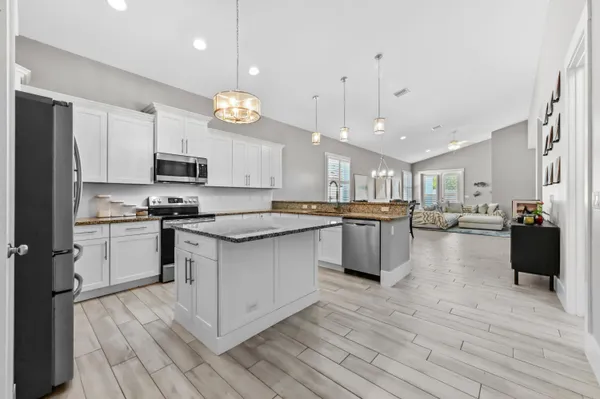 a kitchen with stainless steel appliances kitchen island granite countertop a stove a sink a refrigerator and a microwave