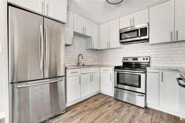 a kitchen with cabinets stainless steel appliances and wooden floor