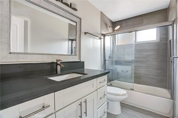 a bathroom with a granite countertop sink toilet a mirror and shower