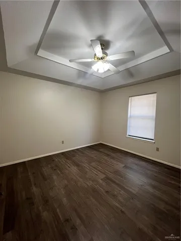 an empty room with wooden floor and ceiling fan