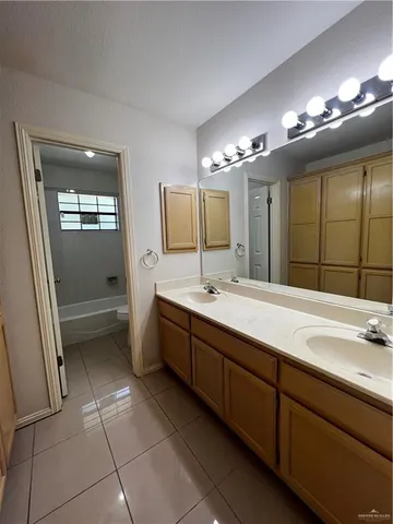 a spacious bathroom with a double vanity sink a mirror and a bathtub