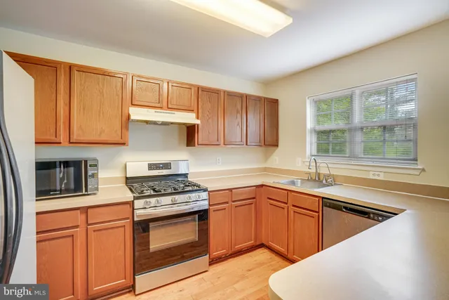 a kitchen with granite countertop a sink stainless steel appliances and cabinets