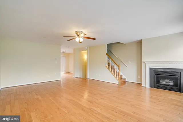 a view of an empty room with wooden floor and a fireplace