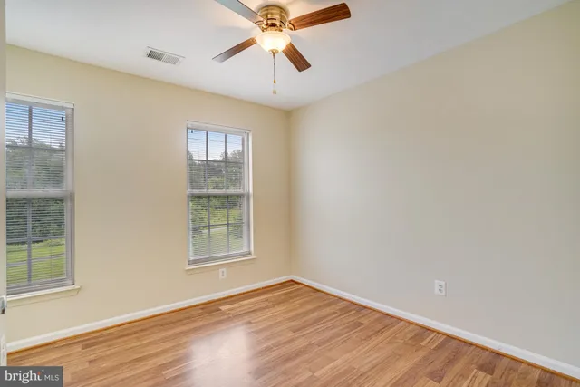 a view of an empty room with window and wooden floor