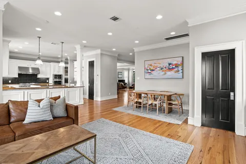 a living room with furniture kitchen view and a wooden floor