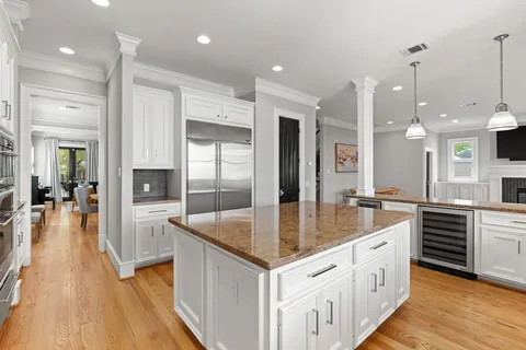 a large kitchen with granite countertop a large counter top a sink stainless steel appliances and cabinets