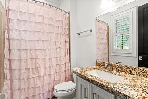 a bathroom with a granite countertop sink a toilet and shower curtain
