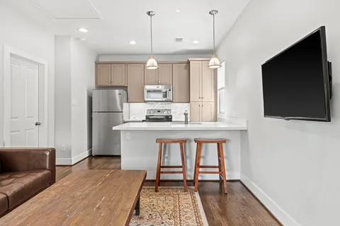 a kitchen with stainless steel appliances kitchen island granite countertop a refrigerator a stove a microwave oven with white cabinets and wooden floor