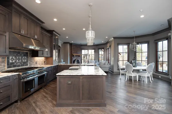 a large kitchen with stainless steel appliances granite countertop a stove and a wooden floors