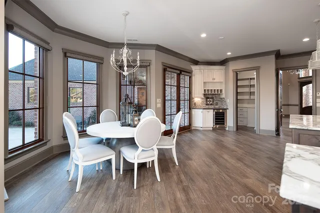 a dining room with wooden floor a chandelier a glass table and chairs