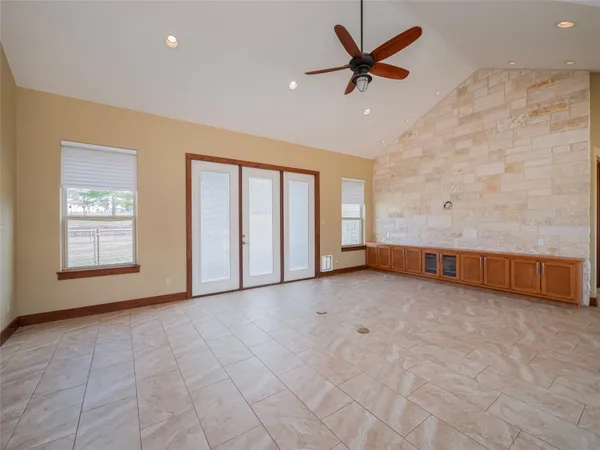 an empty room with chandelier fan and windows