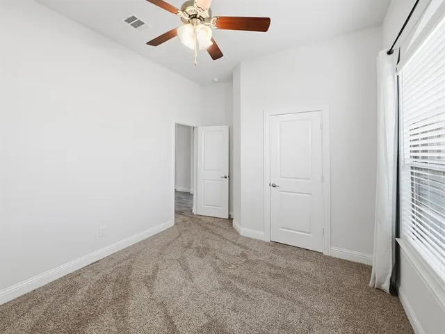 an empty room with closet and a chandelier fan