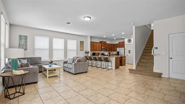 a living room with couches and kitchen view with wooden floor