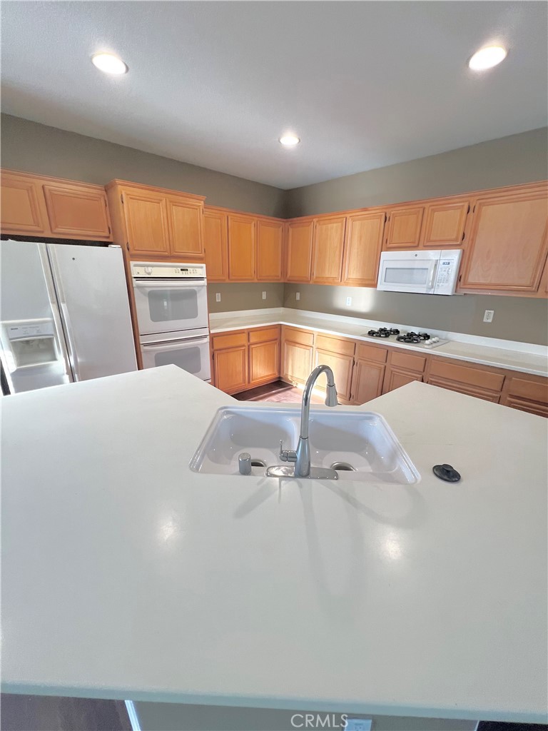 27145 Cherry Grove Court Temecula, CA 92591 - Photo 19 of 61 a kitchen with stainless steel appliances granite countertop a sink a stove and a refrigerator with wooden floor