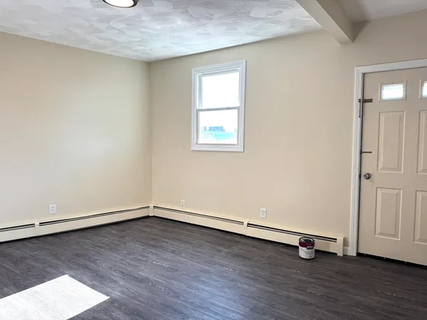 an empty room with wooden floor and window