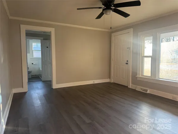 an empty room with wooden floor fan and windows