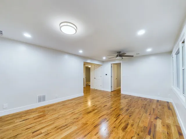 an empty room with wooden floor and natural light