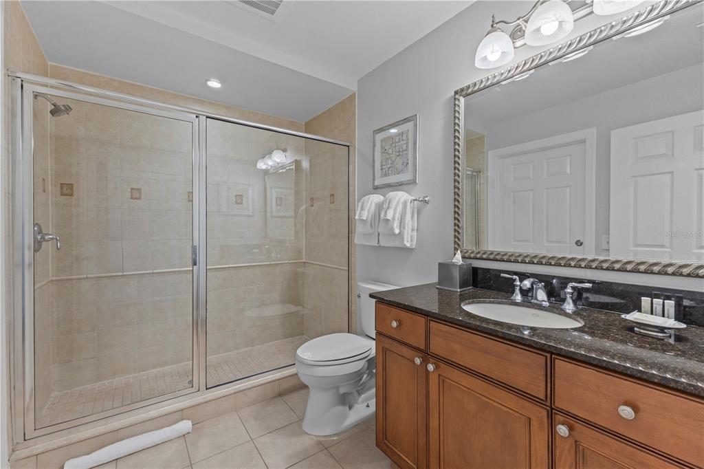 1354 Centre Ct Ridge Drive, Unit 302 Reunion, FL 34747 - Photo 24 of 33 a bathroom with a granite countertop sink a toilet a mirror and shower