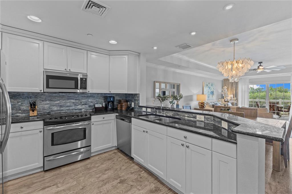 1354 Centre Ct Ridge Drive, Unit 302 Reunion, FL 34747 - Photo 3 of 33 a kitchen with kitchen island granite countertop stainless steel appliances a sink cabinets and a wooden floor