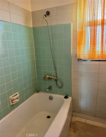 a bathroom with a tub a window and shower