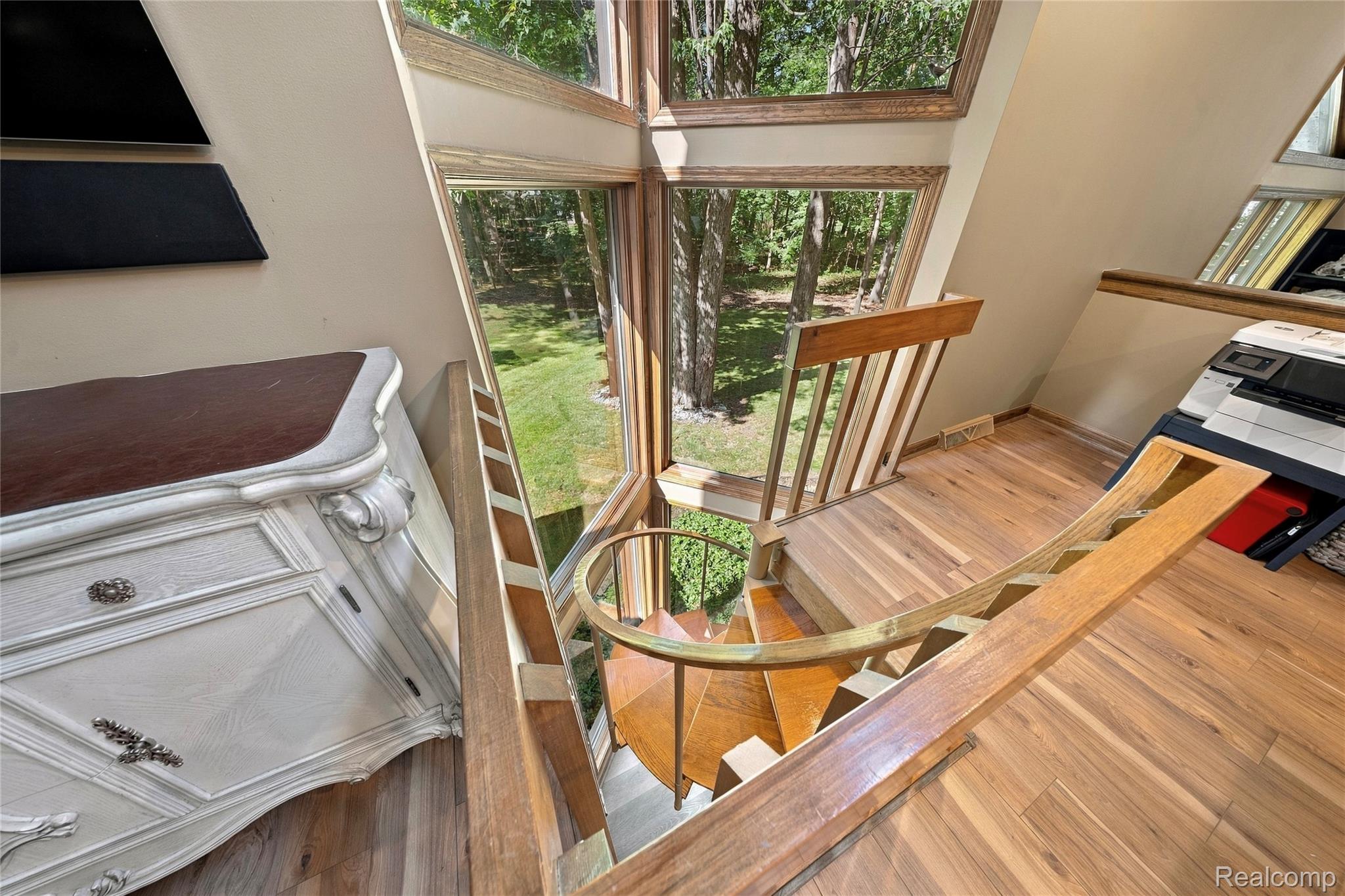 8931 Bridge Road Grosse Ile, MI 48138 - Photo 31 of 55 Wood-finish flooring, spiral staircase, natural wood railings, large window panels, and a painted wall finish