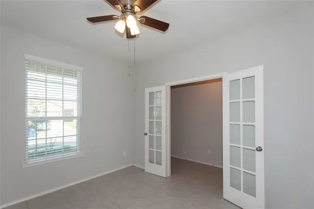 an empty room with windows and fan