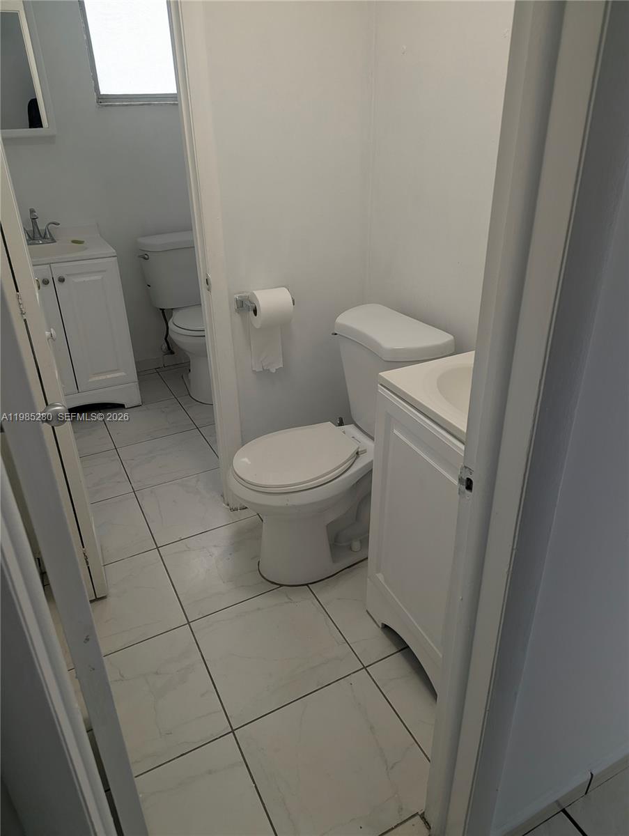 1051 Southwest 1st Street, Unit 411 Miami, FL 33130 - Photo 4 of 8 a white toilet sitting next to a white sink and vanity