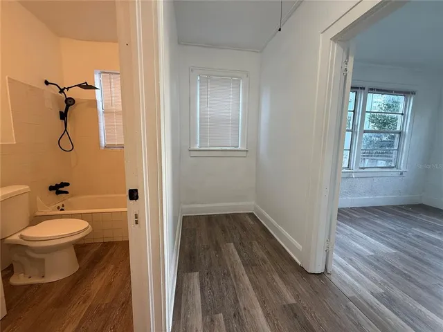 a bathroom with a toilet and a hardwood floor