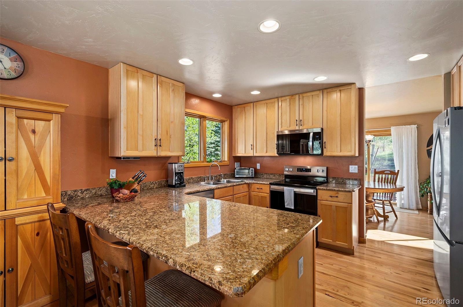 290 Village Road Granby, CO 80446 - Photo 11 of 45 a kitchen with stainless steel appliances granite countertop a stove top oven a sink dishwasher a dining table and chairs with wooden floor