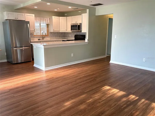 an empty room with wooden floor fan and window