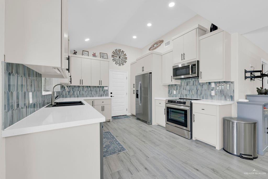 400 Taurus Street Mission, TX 78572 - Photo 6 of 16 Kitchen with stainless steel appliances, tasteful backsplash, light countertops, vaulted ceiling, and recessed lighting