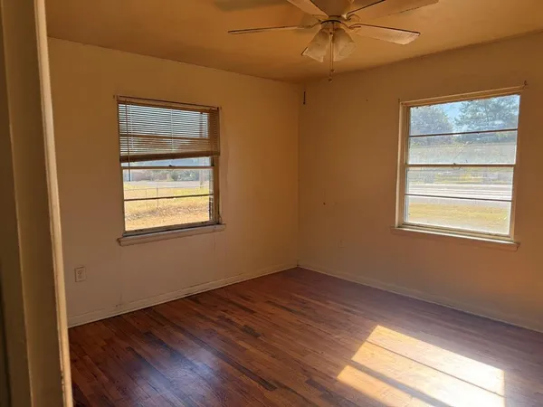 a view of an empty room with wooden floor and a window