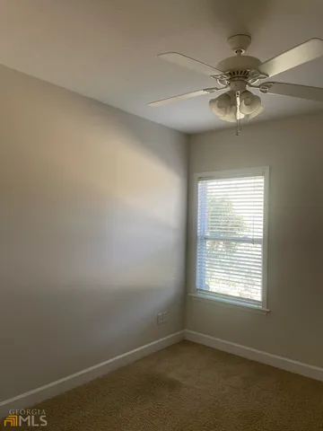 an empty room with a chandelier fan and windows