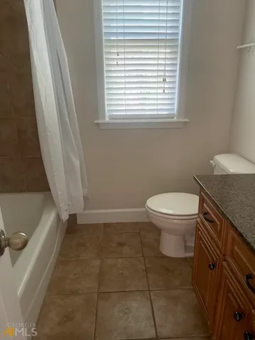 a bathroom with a granite countertop toilet a sink a vanity and a window