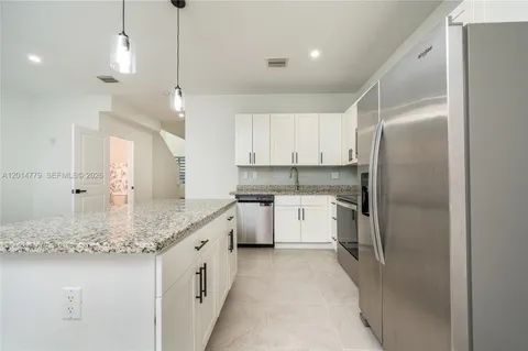 a kitchen with white cabinets and refrigerator