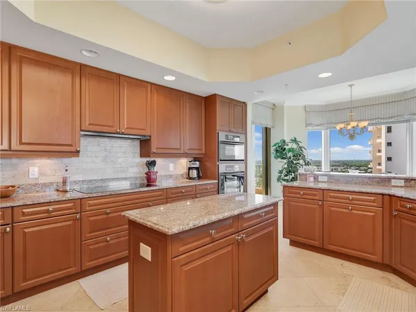 a kitchen with kitchen island granite countertop a sink stove and cabinets