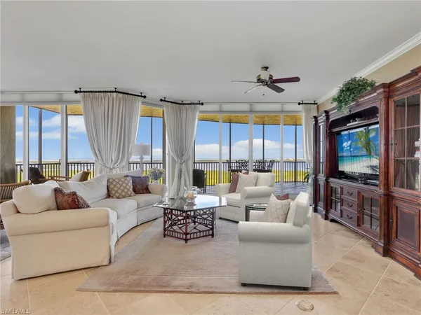 a living room with furniture a flat screen tv and a large window