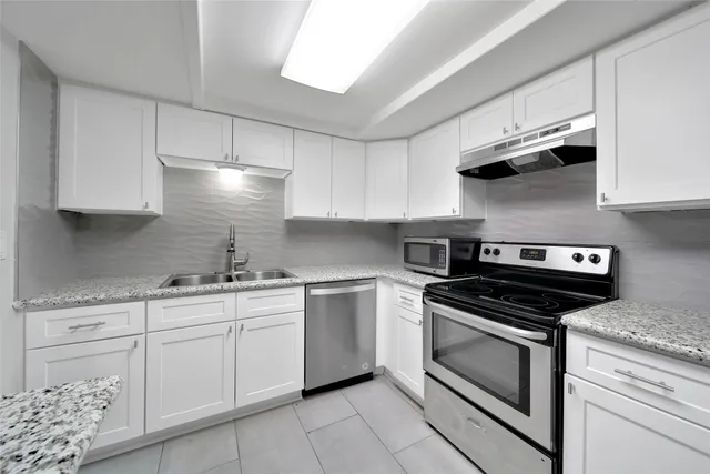 a kitchen with stainless steel appliances white cabinets and a stove top oven