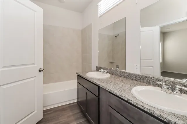 a bathroom with a granite countertop tub sink and mirror