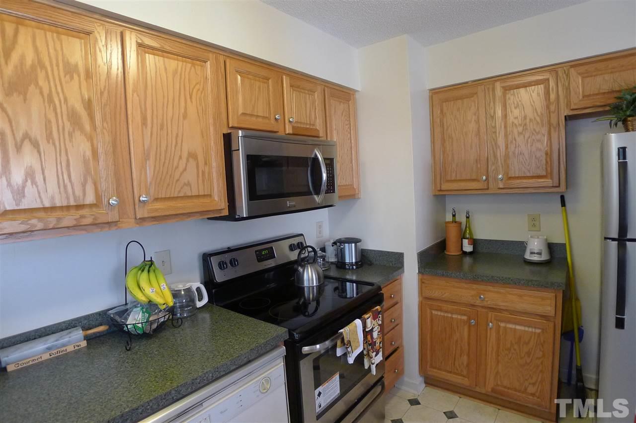 2708 Heathersmith Court Raleigh, NC 27604 - Photo 7 of 25 a kitchen with stainless steel appliances granite countertop a stove a sink dishwasher and microwave with wooden cabinets
