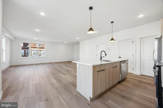 a large kitchen with sink and dishwasher with wooden floor