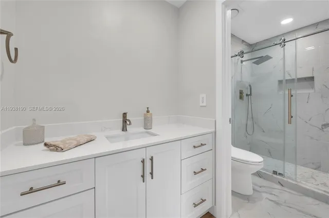 a bathroom with a granite countertop sink a toilet and shower