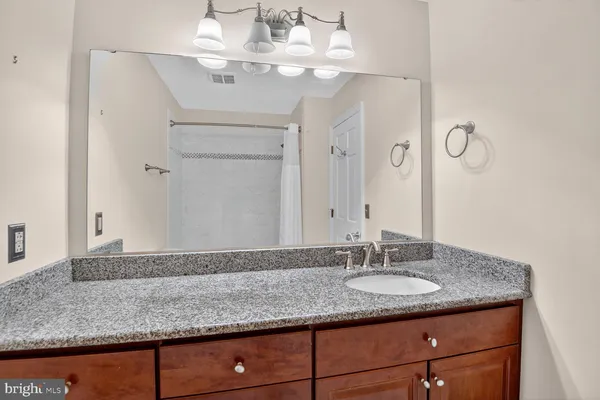 a bathroom with a granite countertop sink and a mirror