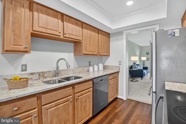 a kitchen with stainless steel appliances granite countertop a sink dishwasher stove and refrigerator with wooden floor