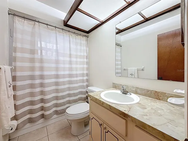 a bathroom with a sink a toilet a mirror and shower curtain