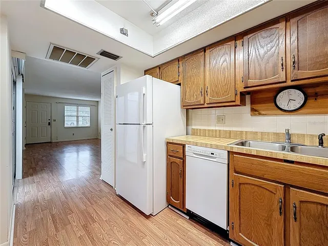 a kitchen with stainless steel appliances granite countertop a refrigerator a sink dishwasher and white cabinets with wooden floor