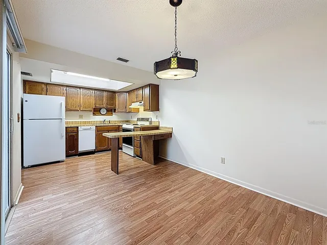 a kitchen with stainless steel appliances granite countertop a sink a stove a refrigerator and island with wooden floor