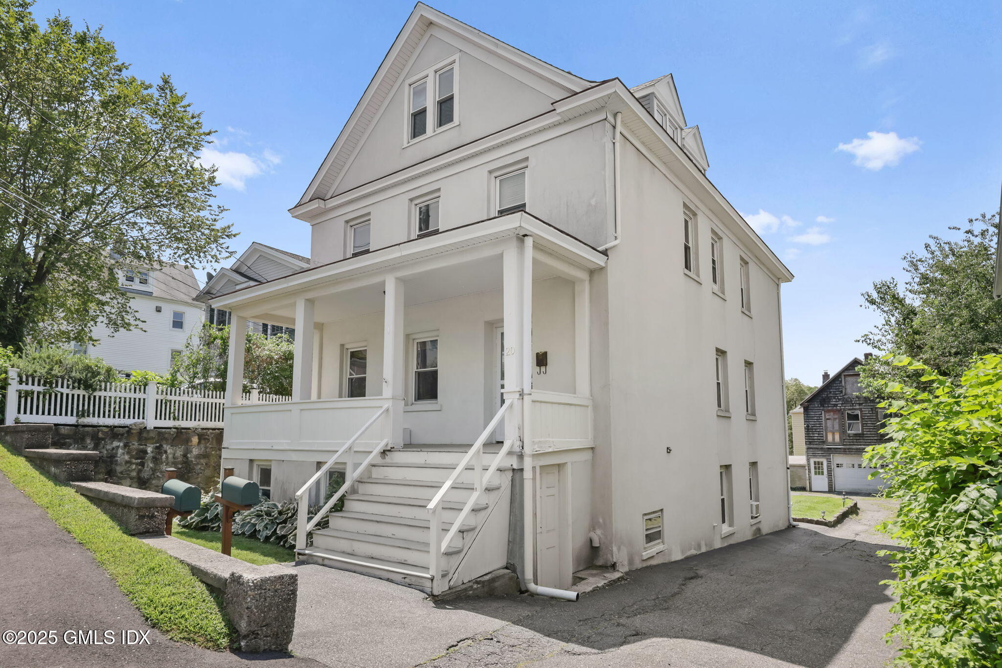 20 Church St W Greenwich, CT 06830 - Photo 1 of 31 a view of a white house with potted plants and a bench