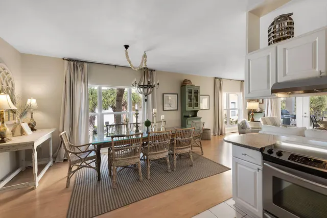 a kitchen with stainless steel appliances granite countertop a stove a refrigerator a kitchen island a dining table and chairs with wooden floor